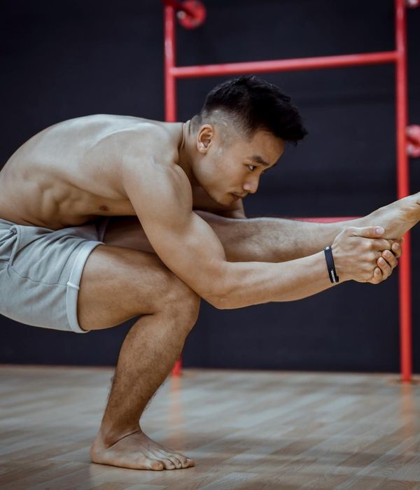 Man in a strong yoga warrior pose in a dark studio.