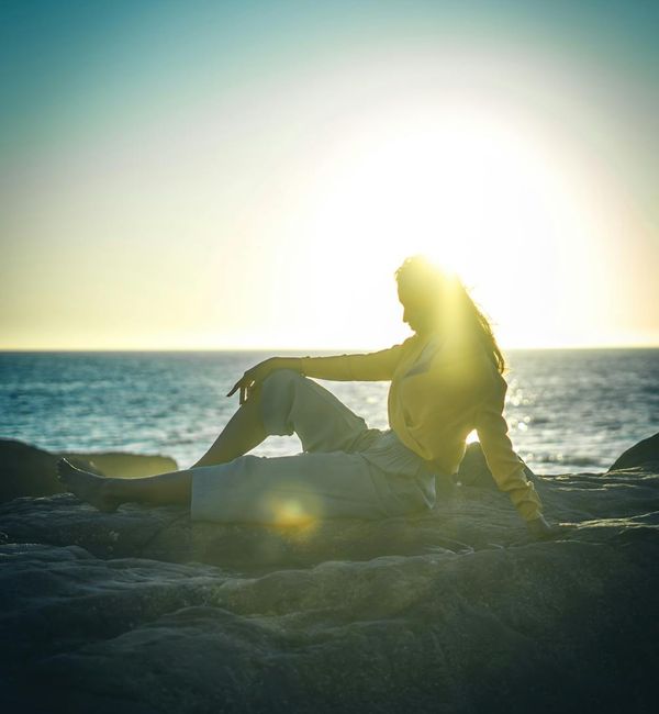 Silhouette of a person in a peaceful meditation pose at sunrise.